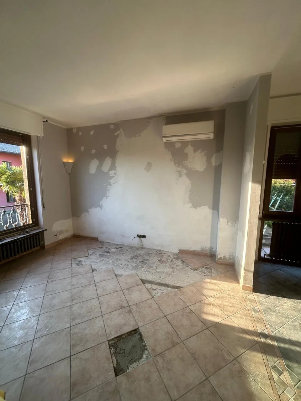 Parete stuccata e piastrelle mancanti nella zona prima occupata dal camino.
